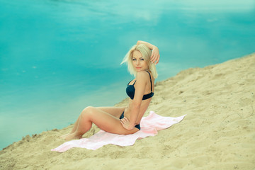 Fototapeta na wymiar beautiful girl in a black bikini on the beach. Outdoor portrait of tanned girl having fun on sun