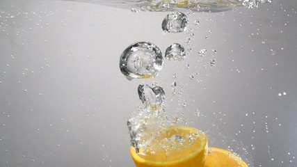 Parts of orange drops under water. slowmotion - Powered by Adobe