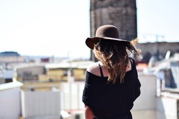 Lonely young woman in brown hat from the back thinking on terraсe, Barcelona, gothic quarter