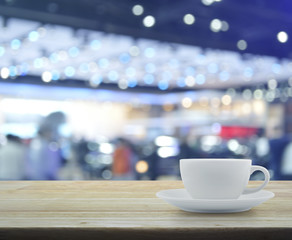White cup on wooden table over defocused light and shadow of sho