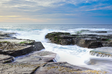 The wave flows over weathered rocks and boulders at North Narrab