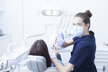 Beautiful woman patient having dental treatment at dentist's office. Woman visiting her dentist - obrazy, fototapety, plakaty