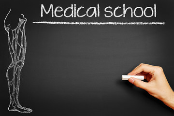 Hand writing "Medical school" on blackboard