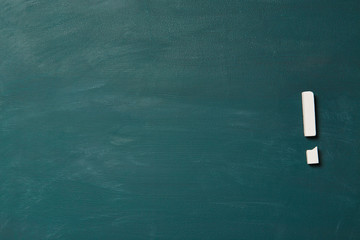 Empty green chalkboard with broken chalk as exclamation point