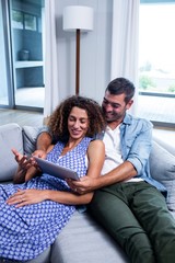 Obraz premium Young couple using a digital tablet on sofa