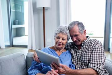 Senior couple using a digital tablet on sofa