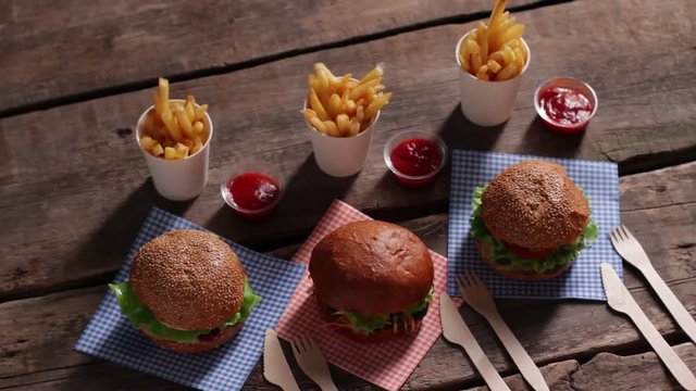 Set of burgers with fries. Cutlery and hamburgers on table. Burgers on old wooden background. Best burgers at retro diner.
