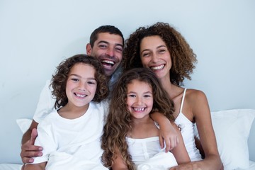 Obraz premium Portrait of family sitting together on bed