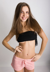 Fototapeta premium leggy blonde girl in pink shorts and a short tank top holding her hair hands
