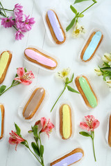 Eclairs with glaze on a white wooden table