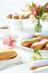 Eclairs with glaze on a white wooden table