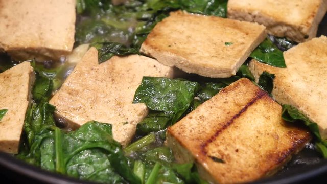 Marinated tofu with leafy spinach close up
