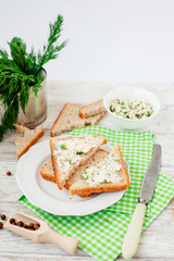 
breakfast or lunch , light sandwiches ,  rye toast with cream cheese , dill and spices on a wooden background
