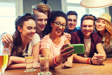 happy friends with smartphone taking selfie at bar