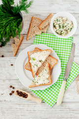 
breakfast or lunch , light sandwiches ,  rye toast with cream cheese , dill and spices on a wooden background
