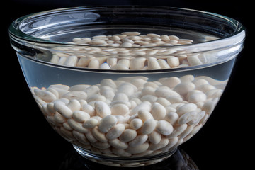 White beans soaked in water in a glass bowl