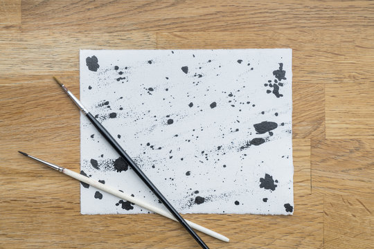 Blots of ink on a white paper on a wooden surface