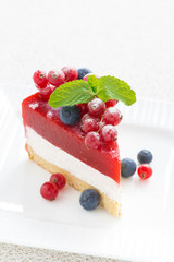 piece of delicious cheesecake with berry jelly on a white plate