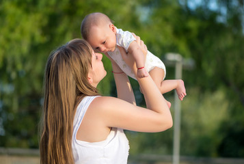 Obraz premium Portrait of happy loving mother and her baby outdoors