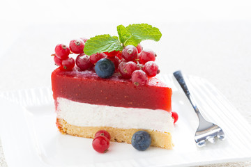 piece of delicious cheesecake with berry jelly on a white plate