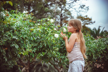 Child with rose flower in spring garden