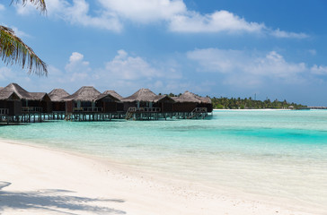 bungalow huts in sea water on exotic resort beach