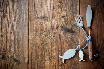 Fish cutlery tied with empty fish shaped tag on wooden table with copy space. Menu card for...