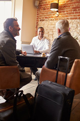 A middle aged gay male couple check in at a boutique hotel