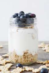 Yogurt with fresh blueberries and cereals on rustic wood
