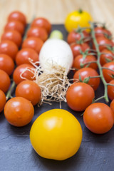 red tomatoes, yellow and scallions on a slate tray
