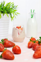 Strawberry milkshake with fresh strawberries and a jug of milk