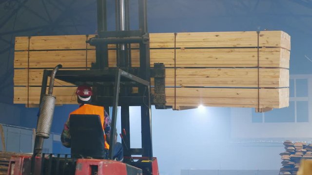 Work at the sawmill: Trucks transporting blocks of wood, warehouse worker with tablet controls work