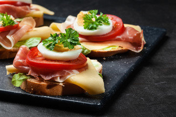 Delicious sandwich with prosciutto ham, cheese, tomato and egg