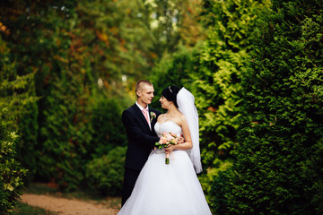 Beautiful bride and handsome groom at wedding day lovely hugging outdoors on nature. Bridal couple, happy newlywed woman and man embracing in green park. Loving wedding couple outdoor.