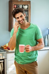 Man talking on the phone and holding a coffee cup in kitchen