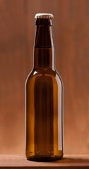 Photo of an small Bottle of beer on wooden table dark lighted up background. Studio shot indoors . No label
