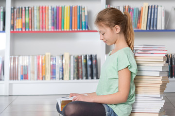 Cute girl reading book in library 
