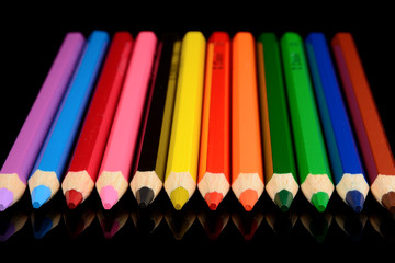 colored pencils isolated on black background with reflection