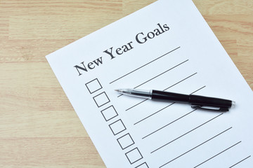 Concept : pen on paper with new year goals word on wood backgrou