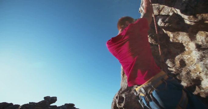 focused Rock climber holding on grip while hanging from boulder