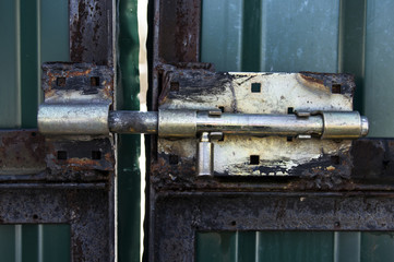 Old rusty metal brass latch roughly velded to green metal gates