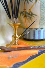 Burning incense sticks. 
Burning incense sticks and oriental ceramic vase are at silk fabric