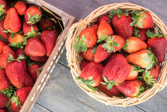 Fresh, ripe strawberries in a basket and in crate of local farmers market.