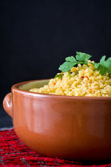 Couscous with vegetables on black stone
