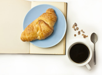 Croissant, open book, black coffee, cane sugar, small spoon