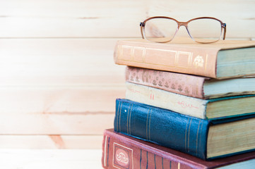 Fototapeta na wymiar Stack of books with glasses on wooden desk, 