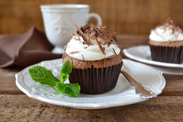 Chocolate cupcakes with cream and chocolate on a wooden backgrou