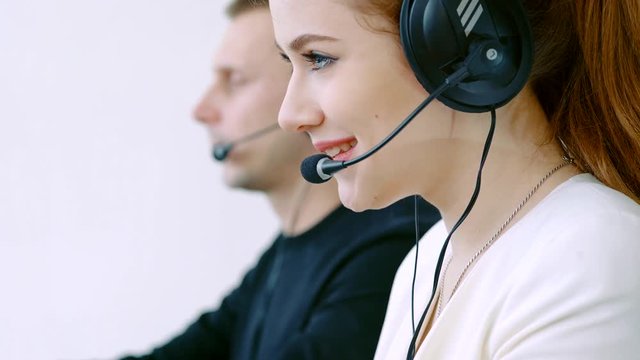 Young employee working with a headset and accompanied by her team