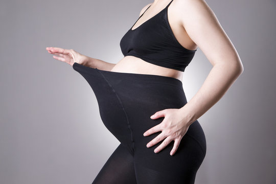 Pregnant woman in black tights for pregnant women on gray background