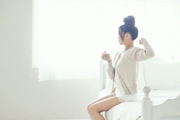 Obraz na płótnie Canvas ベッドでコーヒーを飲む女性